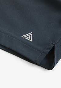 Dark navy athletic fabric with a smooth texture, featuring a silver triangular logo and perforated accents at the hem.
