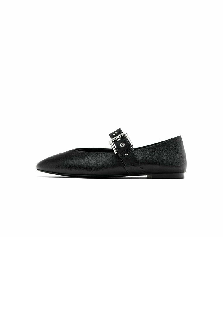 Chaussure plate Mary Jane noire avec bout pointu et bride avec boucle argentée sur fond blanc.