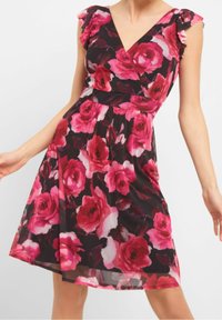 Kwiatowa sukienka o kroju wrap z różowym i białym wzorem róż na czarnym tle, z falbaniastymi rękawami i dopasowaną talią. Lekki materiał.