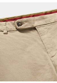 Beżowe bawełniane spodnie o gładkiej fakturze, z brązowym zapięciem na guzik i kolorowym paskiem w paski.