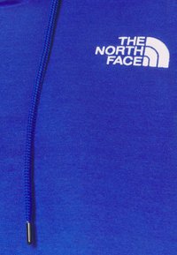 Felpa blu realizzata in morbido tessuto. Presenta un logo bianco contrastante di "THE NORTH FACE" e un cordino intrecciato con aglet in argento.