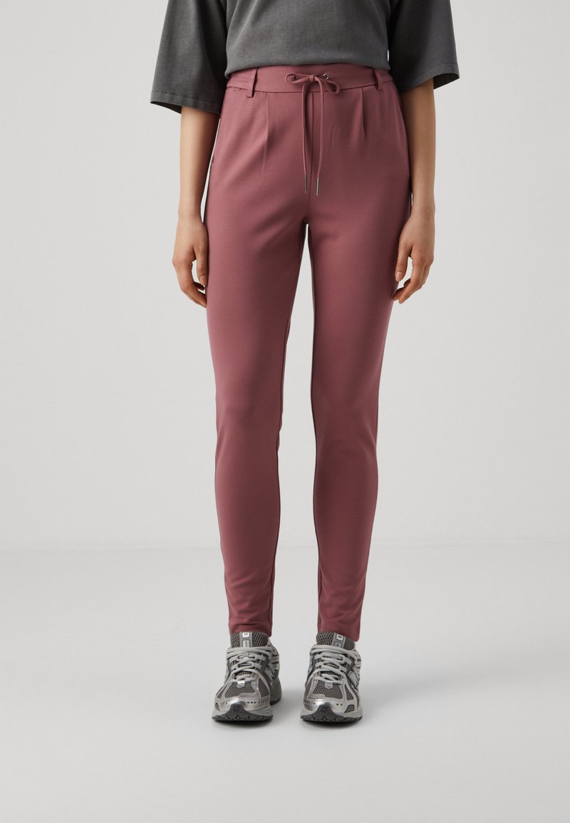 Slim-fit, roze sportbroek met een tailleband met trekkoord. Gemaakt van zachte, rekbare stof. Gecombineerd met grijze sneakers met netdetails.