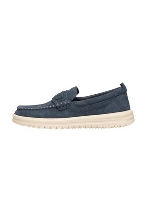 Chaussure à enfiler en daim bleu marine avec des détails de couture et une semelle en caoutchouc beige. Design bas et profilé avec un bout arrondi. Sans lacets.