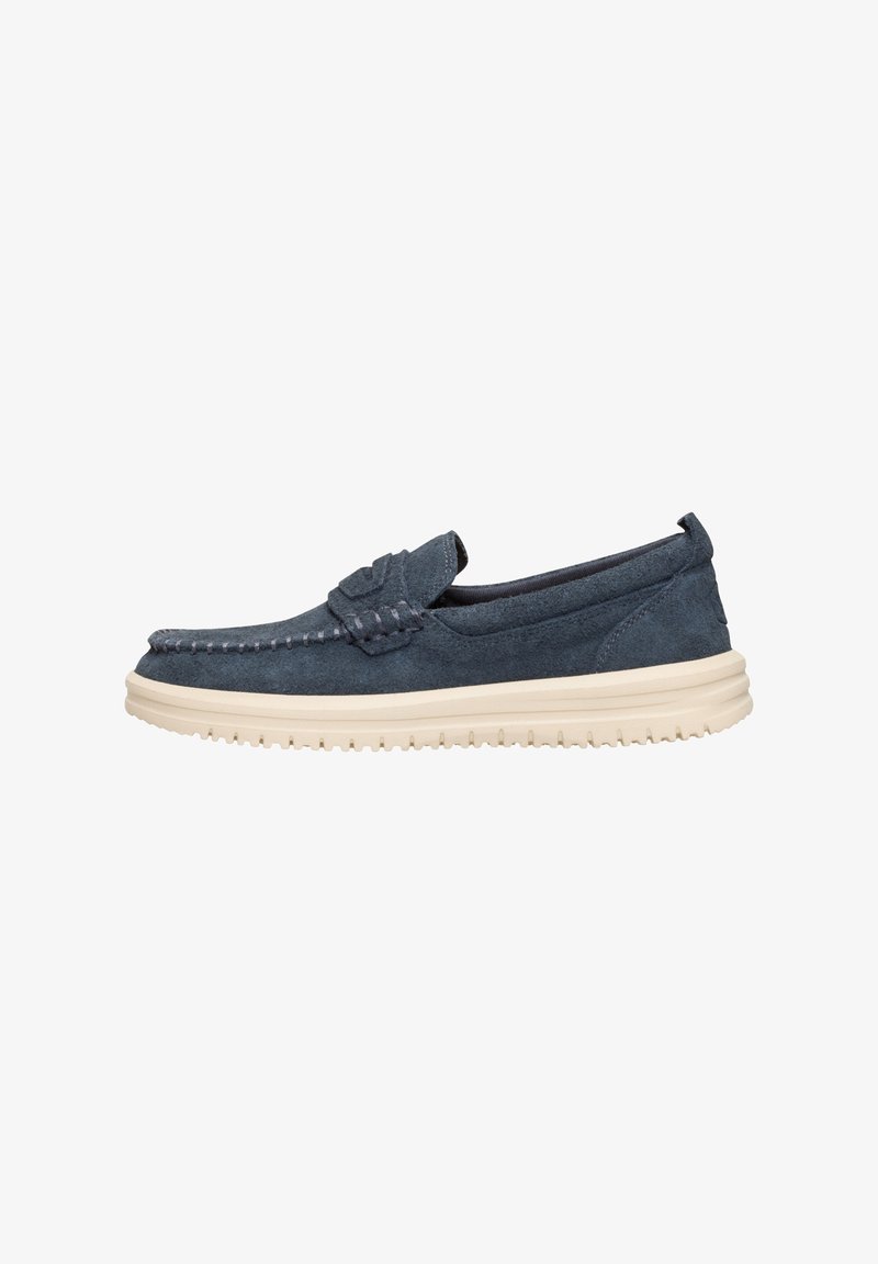 Zapato de ante tipo slip-on en navy con detalle de costura y suela de goma en beige. Diseño de perfil bajo con puntera redonda. Sin cordones.
