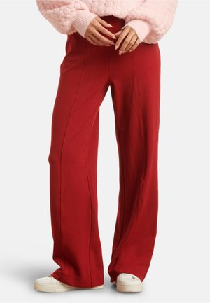 Red wide-leg pants made of soft fabric, featuring vertical seams, a comfortable waistband, and paired with white sneakers.