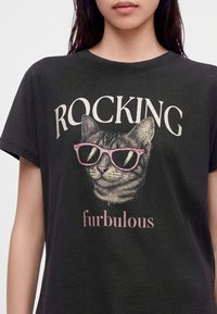 Μαύρο μπλουζάκι με μια γάτα που φοράει ροζ γυαλιά ηλίου και τις λέξεις "ROCKING" πάνω και "furbulous" κάτω από την εικόνα της γάτας.
