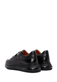 Sneaker nere in pelle con suole ammortizzate, dettagli testurizzati e interno arancione. Forma arrotondata con una finitura liscia e dettagli di cucitura sottili.