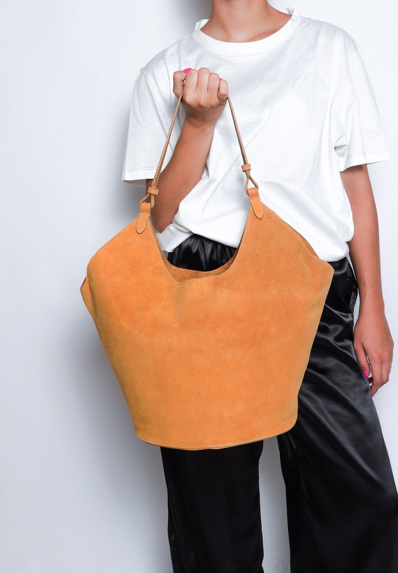 Borsa a tote in suede arancione caldo con forma morbida, doppio manico e cuciture tonali. Texture liscia, design non strutturato.