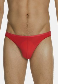 Costume da bagno rosso in tessuto morbido, con design a vita bassa, fascia elastica in vita e copertura minima. Senza motivi o accenti visibili.