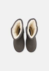 Bottes en daim gris avec une doublure douce en fausse fourrure crème, dessus arrondis et coutures décoratives le long des coutures. Aucun élément métallique ou accent visible.