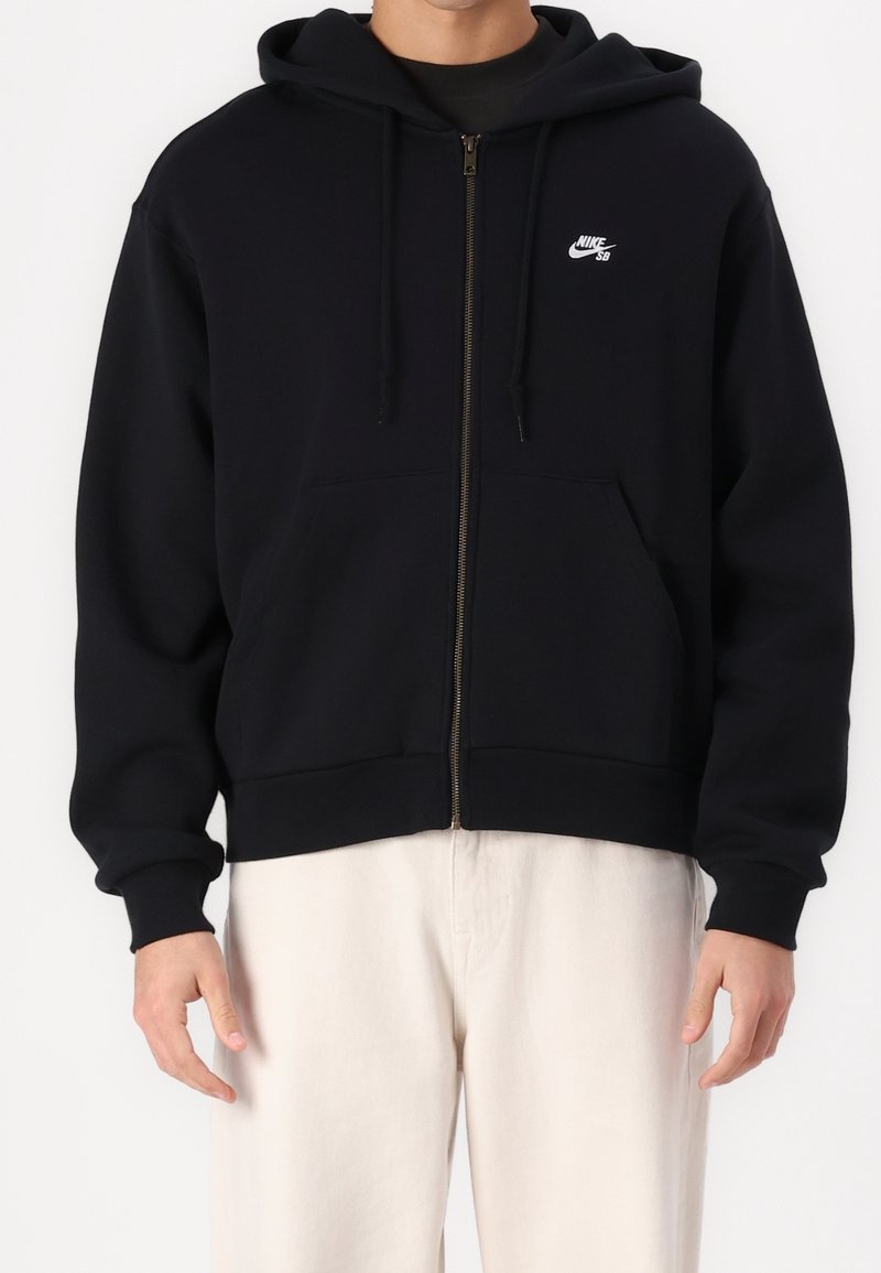 Felpa nera con zip realizzata in misto cotone, dotata di una tasca frontale, cappuccio con coulisse e un logo Nike bianco sul lato sinistro del petto.