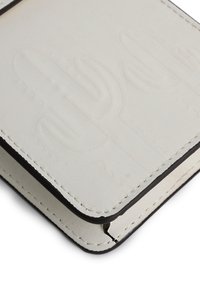 Kaktus-prägedes Portemonnaie aus off-weißem Leder mit schwarzen Kanten, das über eine subtile Textur und sichtbare Nähte verfügt.