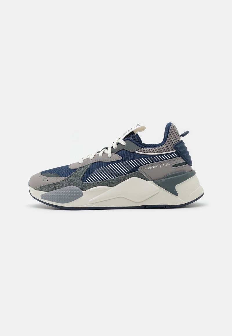 Vue latérale d'une chaussure de sport bleue, grise et blanche avec des lacets blancs et une semelle rembourrée.