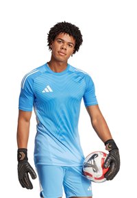 Maglietta atletica azzurro chiaro con un motivo a gradiente, pantaloni corti coordinati e guanti da portiere neri che tengono un pallone da calcio con un motivo.