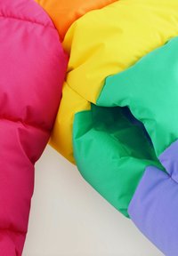 Kleurrijke pufferjack in segmenten van roze, oranje, geel, groen en blauw. Gevoelige, zachte stof met zichtbare stikaccenten.
