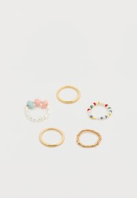 Πέντε δαχτυλίδια: δύο χρυσά μεταλλικά, ένα με χάντρες και πολύχρωμες λεπτομέρειες, ένα με παστέλ χάντρες και μαργαριτάρια, και ένα με μικρές χρυσές χάντρες.