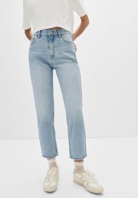 Ljusblå högmidjade jeans med rak passform, med en klassisk knäppning och subtila blekningar, kombinerat med beige sneakers.