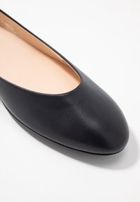 Black leather ballet flat with a rounded toe and low cut silhouette. Smooth texture and minimalistic design without visible hardware.