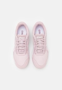 Ljust rosa träningsskor med en strukturerad ovandel, snörning, vadderad krage och vit sula med geometriska mönster.