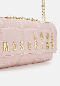 Borsa a tracolla trapuntata rosa con lettering dorato "LOVE MOSCHINO". Presenta una tracolla a catena e una texture liscia. Dettagli cuciti e accenti metallici visibili.
