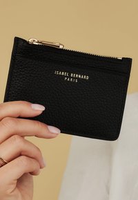 Schwarzer strukturierten Leder-Kartenhalter mit goldfarbenem Logo, Reißverschluss und Fächern für Karten. Glatte Oberfläche und minimalistisches Design.