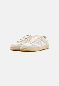 Hvite og beige joggesko med overdel i lær og semsket skinn, perforert tåboks, beige snøring og teksturert gummisåle.