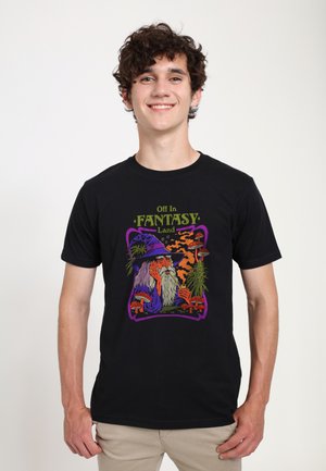 T-shirt noir avec un graphisme coloré d'un sorcier portant un chapeau violet, des champignons et des plantes, le tout entouré d'une bordure décorative.