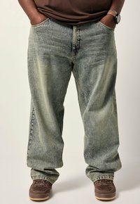 Lysblå baggy denim jeans med falmet struktur og fem-lomme design, parret med brune snørebåndssko.