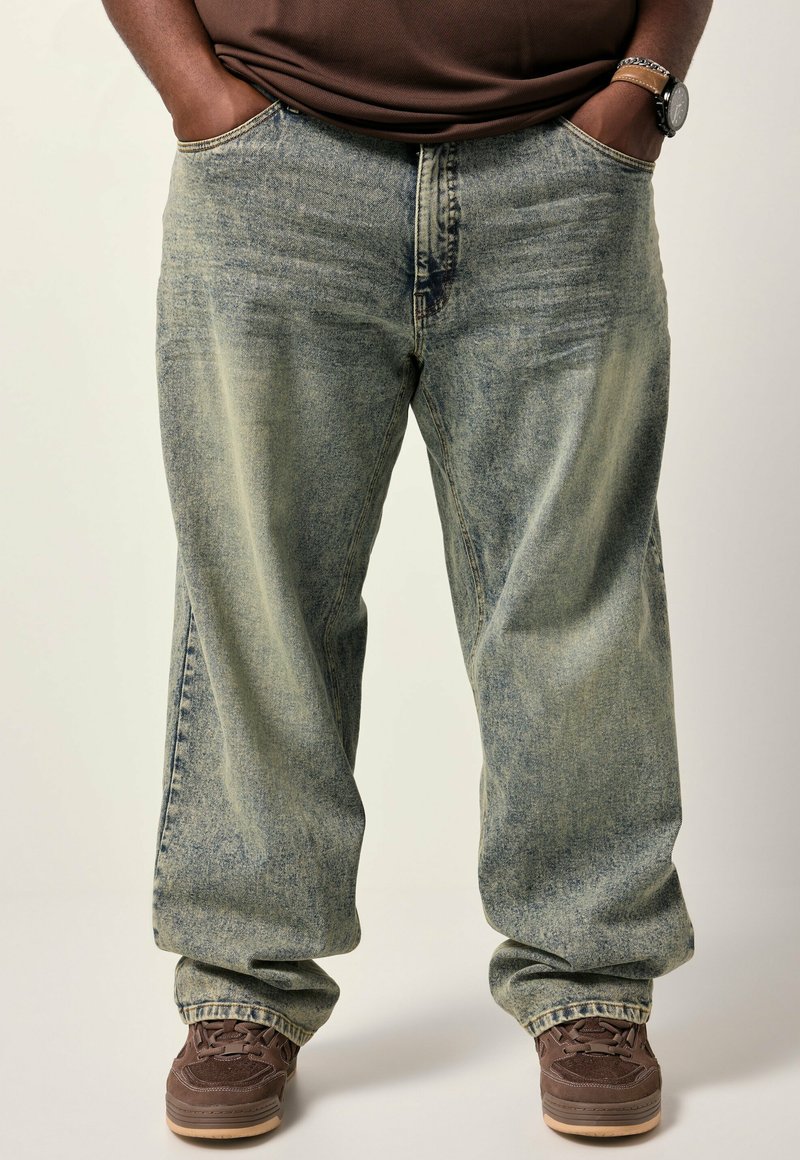 Lysblå baggy denim jeans med falmet struktur og fem-lomme design, parret med brune snørebåndssko.