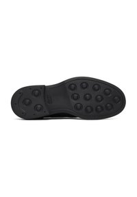 Zwarte rubberen schoenzool met een glad oppervlak en afgeronde, gestructureerde grip in een cirkelpatroon voor betere grip.