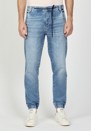Light blue denim jogger pants with an elastic waistband, drawstring detail, and cuffs at the ankles. Smooth texture and casual fit.