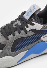 Sneaker dengan bagian atas suede abu-abu dan mesh hitam, aksen biru, rincian berbulu, dan tali sepatu hitam. Dilengkapi dengan sol empuk untuk kenyamanan.