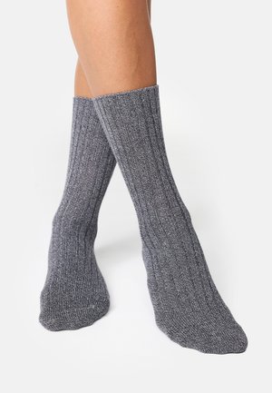 Grå ribstrikkede sokker med tekstureret strik, midt på læggen, med et diskret design og afsluttede kanter uden mønstre eller logoer.