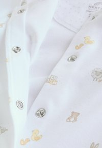 Body en coton blanc avec des pressions et des motifs pastel subtils d'animaux comme des canards et des ours en peluche, avec une finition douce et texturée.