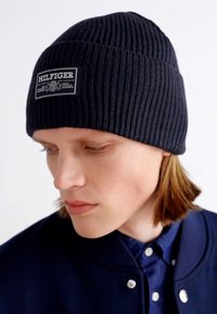 Berretto a coste di colore navy con un'etichetta con la scritta "HILFIGER." Tessuto morbido e vestibilità aderente, progettato per garantire calore nelle giornate più fredde.