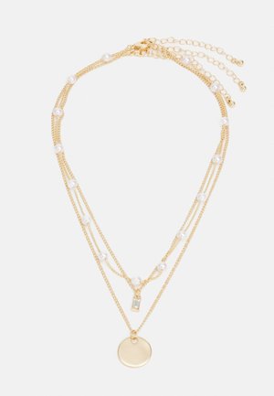 Gold-tone layered necklace with multiple chains, pearls, a rectangular pendant, and a circular charm. Textured and mixed materials.