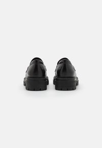 Scarpe in pelle nera con finitura liscia, punta arrotondata e suola in gomma spessa; design minimalista senza accenti o motivi prominenti.