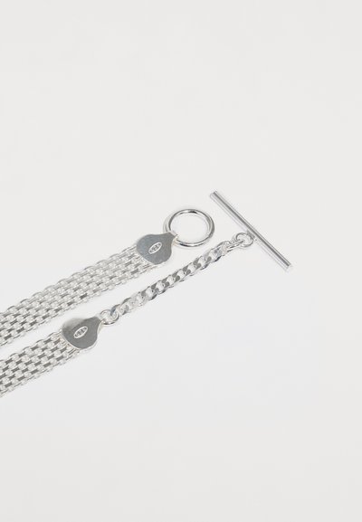 Sølv multi-kæde armbånd med et tekstureret fladt led-design, åben ringlås og en toggle-lukning med et hjerteformet vedhæng.