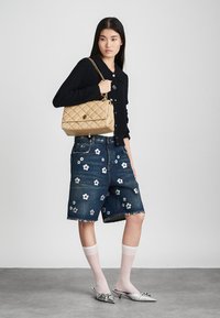 Beige quilted handbag with chain strap, dark knitted cardigan, blue denim shorts with floral embroidery, white knee-high socks, silver flats.