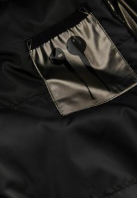 Schwarzer Stoff mit glatter Textur und einer silbernen Satin-Tasche. Die Tasche zeigt ein grafisches Motiv von zwei schwarzen Ohrhörern mit Tropfen.
