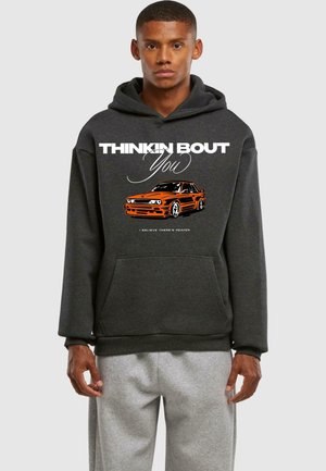 Hoodie grigio scuro con una grafica audace di un'auto arancione e il testo "THINKIN BOUT You" in bianco. Tessuto morbido, tasca frontale tipo kangaroo, polsini a costine.