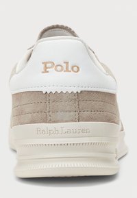 Sneaker beige in suede con dettagli in pelle bianca, caratterizzato dal logo "Polo" in rilievo e da un design testurizzato. Suola in gomma per una maggiore aderenza.