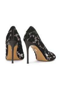 Mustat korkokengät tikkuvastoineen, joissa on läpikuultava pitsinen kukkakuvio ja vaaleanruskeat pohjat.