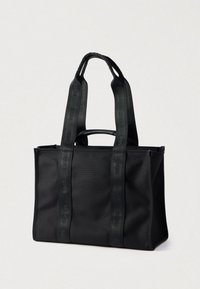 Μαύρη τσάντα ώμου από ύφασμα με ορθογώνιο σχήμα. Διαθέτει διπλές λαβές στην κορυφή και εμφανή λουράκια με λογότυπο στα πλευρά.