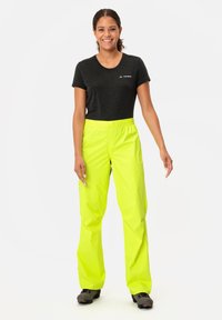 Neon yellow waterproof pants with an elastic waistband, paired with a dark gray t-shirt featuring a small logo.