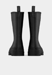 Paar schwarze hohe Gummistiefel mit strukturierten Sohlen und markenprägten Zuglaschen an der Rückseite vor weißem Hintergrund.