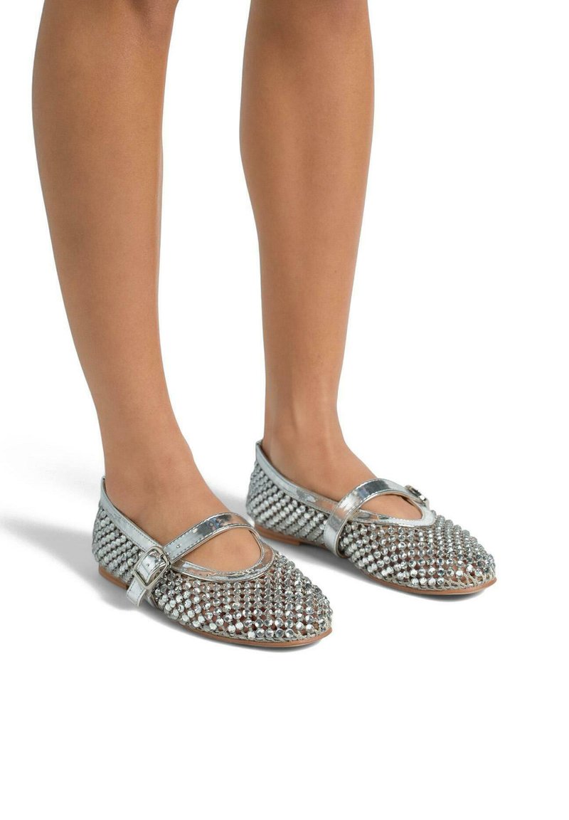 Chaussures plates argentées avec une sangle Mary Jane, présentant un dessus texturé couvert de petits clous métalliques décoratifs et un design de bout pointu.