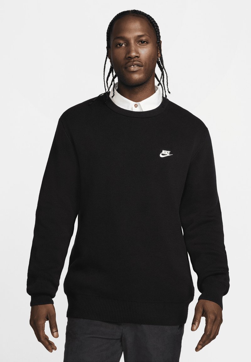 Μαύρη πλεκτή μπλούζα με στρογγυλή λαιμόκοψη και μακρύ μανίκι. Διαθέτει το λευκό λογότυπο Nike στην αριστερή πλευρά του στήθους και ριμπ μανίκια και στρίφωμα.