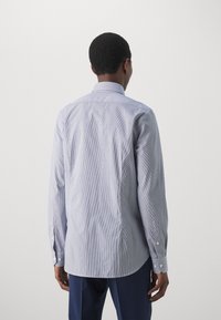 Camicia a righe blu e bianca con maniche lunghe, polsini con bottone, colletto e orlo arrotondato. La trama del tessuto appare liscia e leggera.