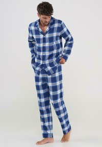 Conjunto de pijama a cuadros en azul y blanco, hecho de tela suave; camisa de botón con cuello y mangas largas, pantalones a juego con un corte holgado.